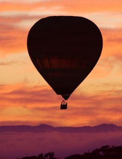 Mongolfiera al tramonto, cielo infuocato e montagne serene.