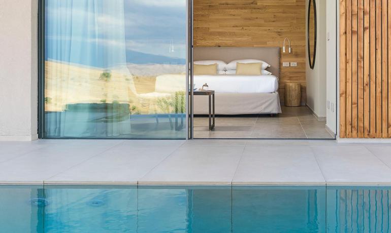 Camera elegante con vista piscina e paesaggio sereno.
