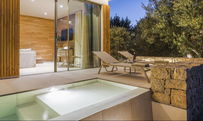 Elegante terrazza con piscina, luci soffuse, natura e relax serale.