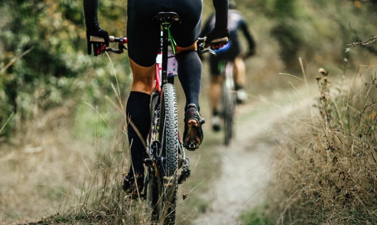 Ciclisti su sentiero sterrato, natura selvaggia, avventura e libertà.