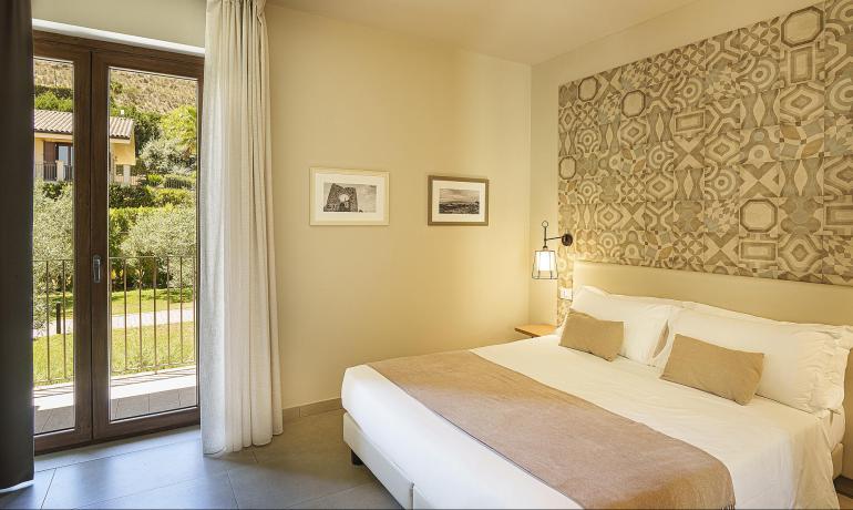 Camera accogliente con letto comodo, decorazioni eleganti e vista giardino.