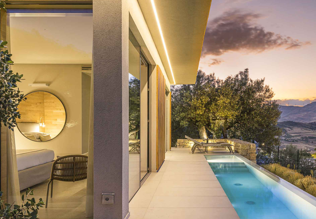 Villa moderna con piscina, vista panoramica al tramonto e interni eleganti.