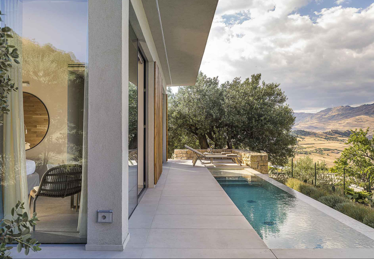 Moderna villa con piscina e vista panoramica su colline e alberi.