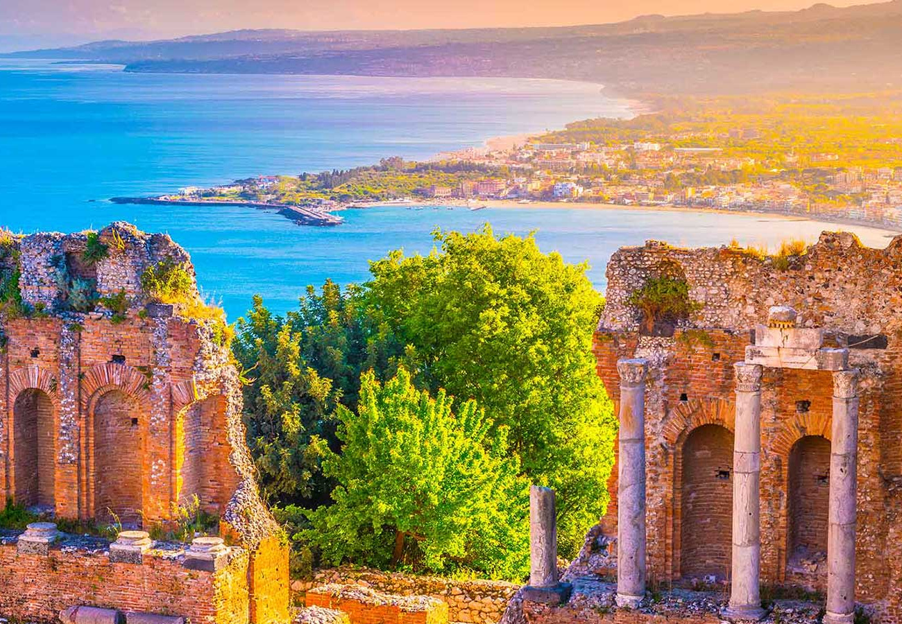 Rovine antiche con vista sul mare e paesaggio costiero al tramonto.