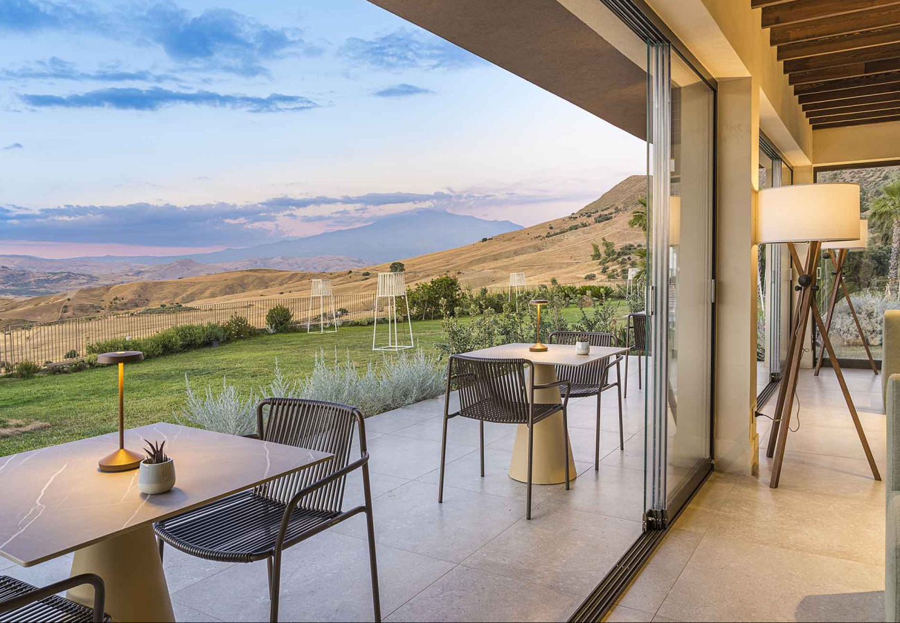 Terrazza moderna con vista panoramica su colline al tramonto, arredi eleganti.