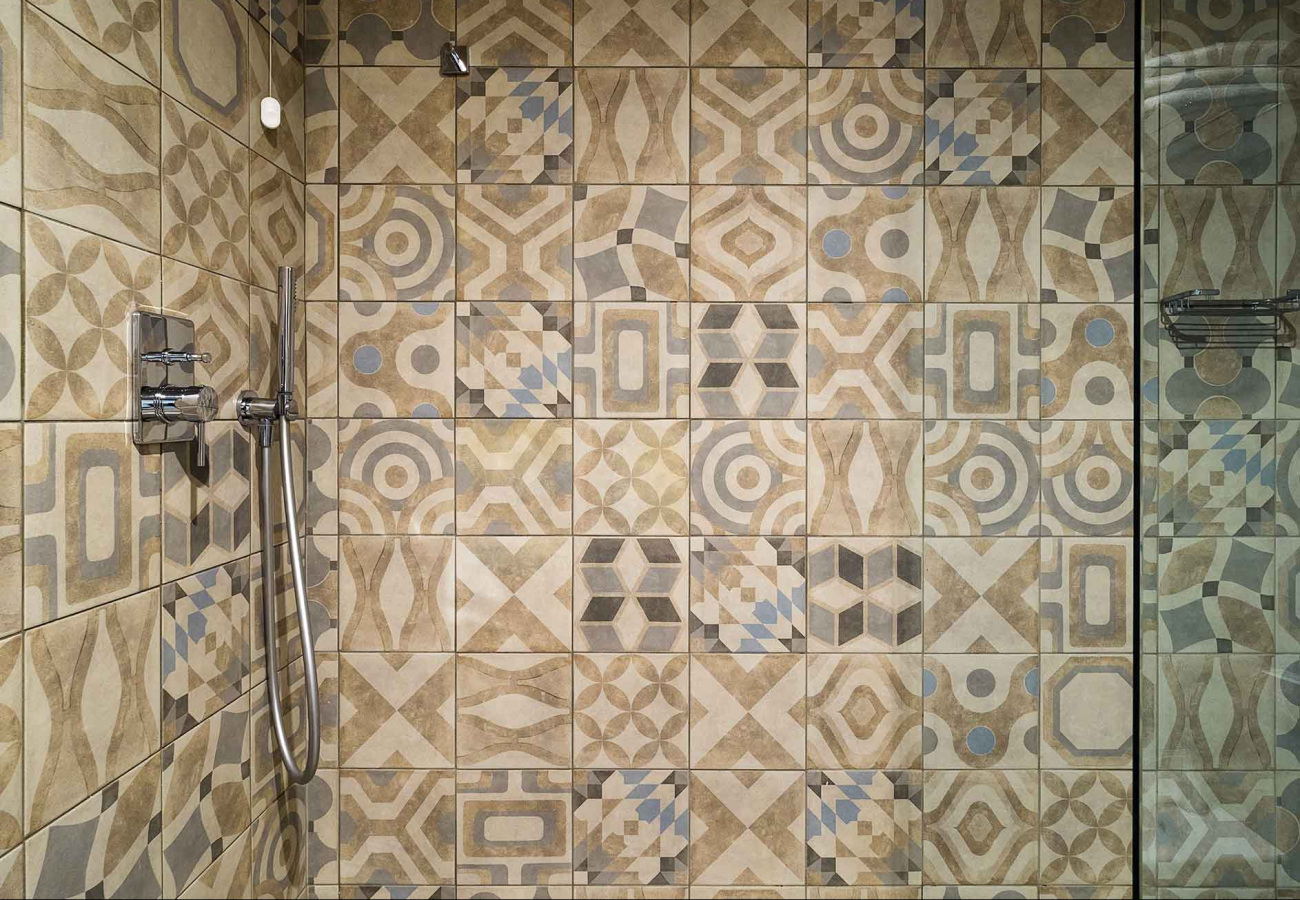 Piastrelle geometriche colorate in un bagno con doccia moderna e rubinetteria cromata.