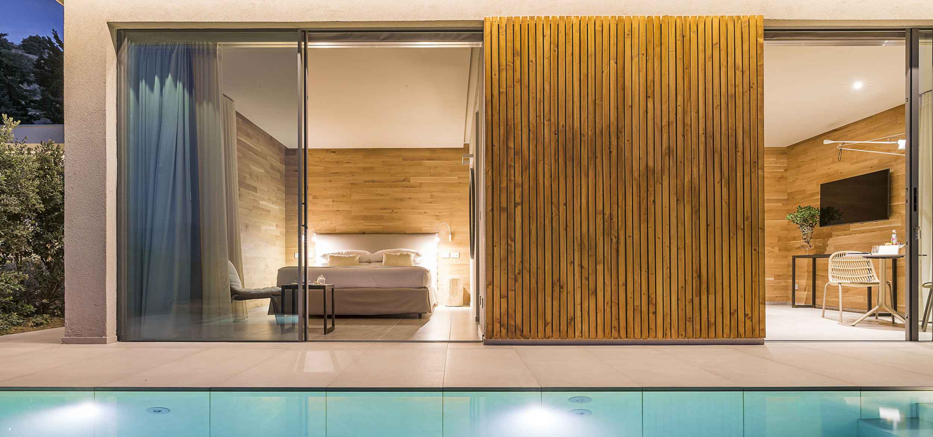 Camera moderna con piscina, legno e ampie vetrate.