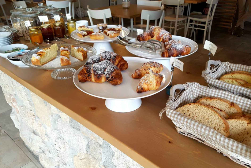 Buffet di colazione con cornetti, torte, pane e marmellate in barattolo.