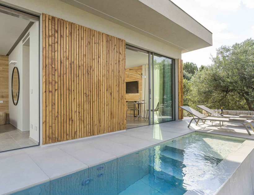 Villa moderna con piscina, pareti in legno e ampie vetrate.