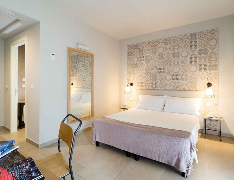 Camera moderna con letto matrimoniale, decorazioni geometriche e illuminazione accogliente.